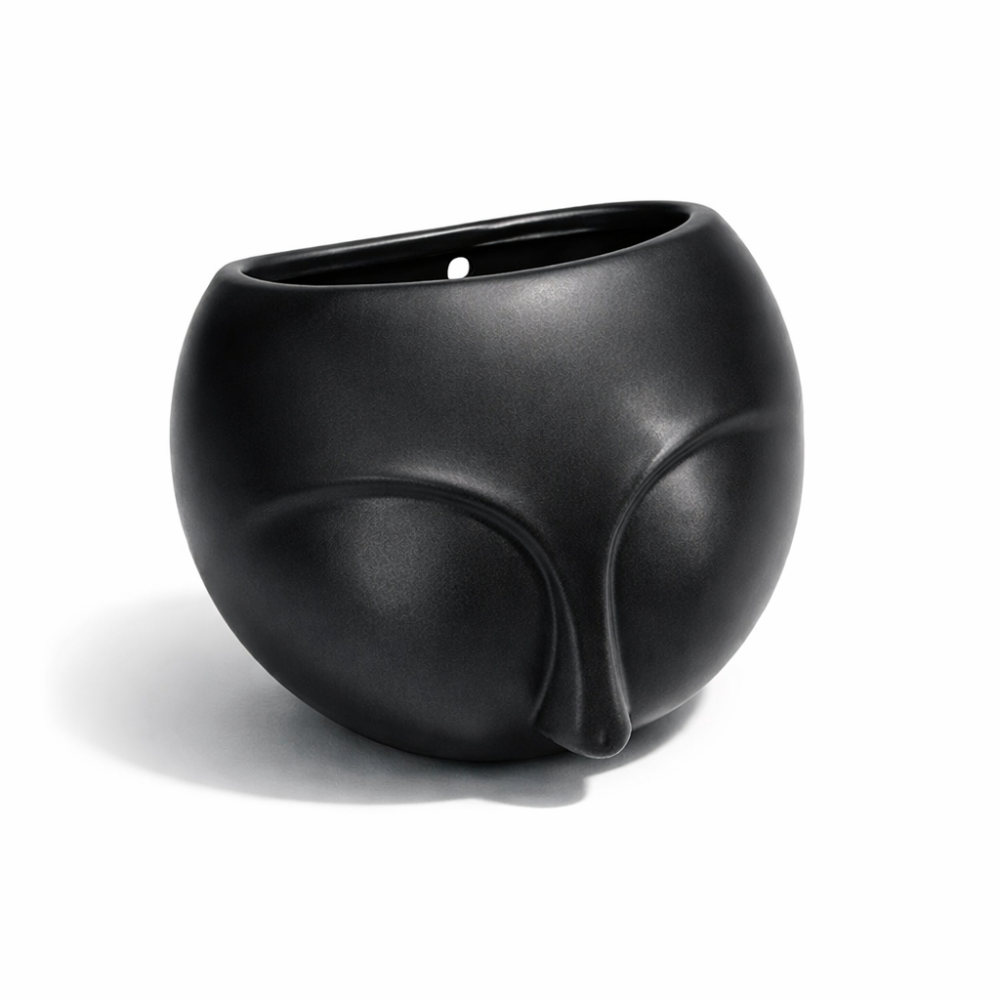 Pequeña maceta de pared de cerámica negra con motivo de rostro esculpido.