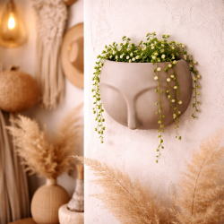 Piccolo coprivaso da parete grigio-beige con motivo a volto scolpito